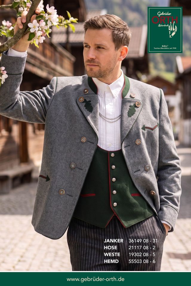 Traditionelle Lederhose mit Weste und Jacke, geblümte Blumen in der Hand, Trachtenlook.