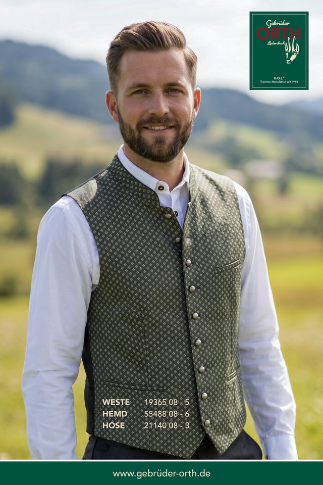 Mann trägt traditionelles Sakkoweste-Set mit Hemd und Hose vor Berglandschaft, gebrüder-orth.de.