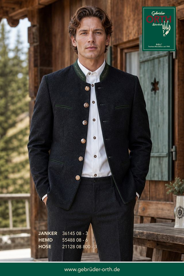 Eleganter Mann in traditionellem Lederhosen-Outfit mit Weste und Anzugjacke vor rustikalem Haus.